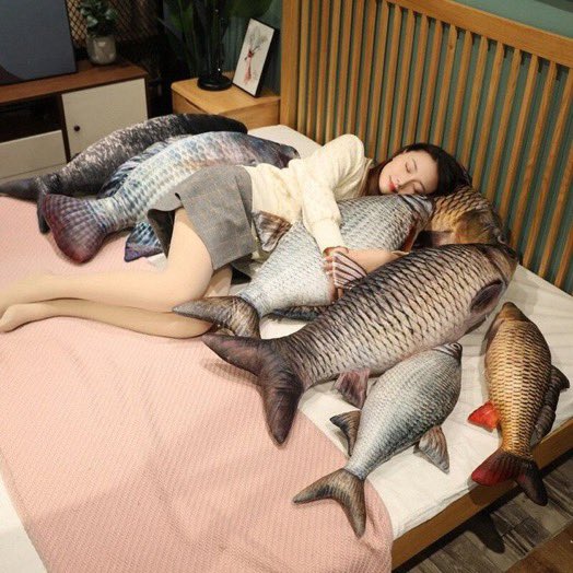 woman in bed cuddling with big fish pillows