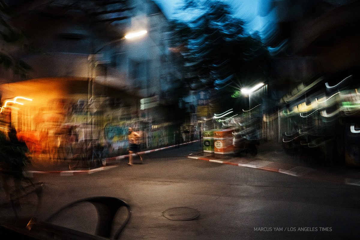 Air raid sirens sound through the alleyways. Meals abandoned. A shirtless man runs to a bomb shelter. More follow after him. Some stay to gaze at twilight blue sky. Incoming rocket attacks from Gaza. Then careful peek out. Life resumes in the Florentine neighborhood in Tel Aviv.