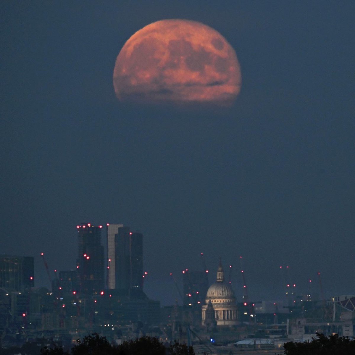 JeffOvers's tweet photo. #Halloween moon. Tonight’s waning full moon resembled a giant jack o’ lantern as rose over #London. From Richmond Park (10 miles distance from the skyline) on an 800mm lens to give this perspective with no image manipulation https://t.co/VNNycm2Bo9