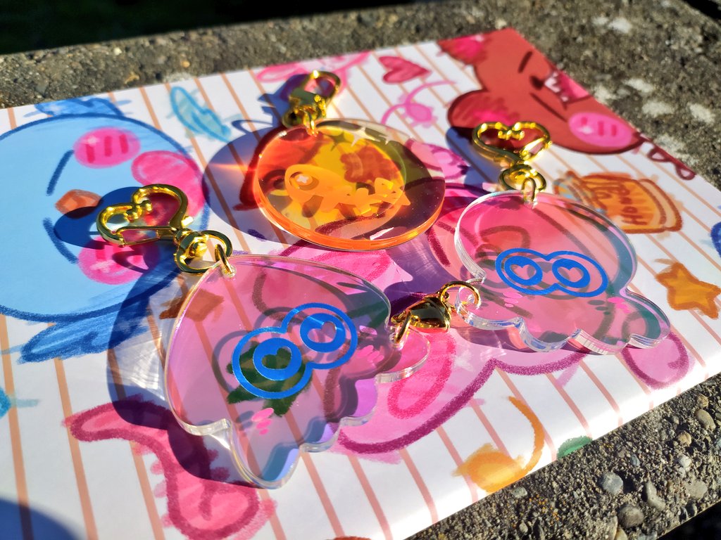 new shi merch drop!!! (pre-orders + local pickup at akimatsuri nov25 post coming soon) ✨ original 'scribbly critters'sticker book ✨ splatoon 'can love bloom in the woomyveemo?' rainbow holo magnetic heart pair charms ✨ splatoon 'yummy salmon eggy' double-sided glitter charm