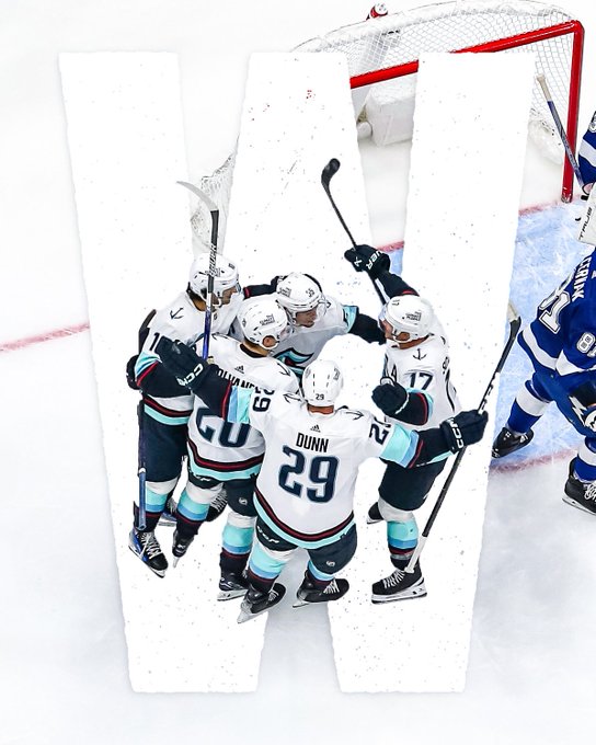 Kraken players celebrating a goal with a big “W” photoshopped behind them