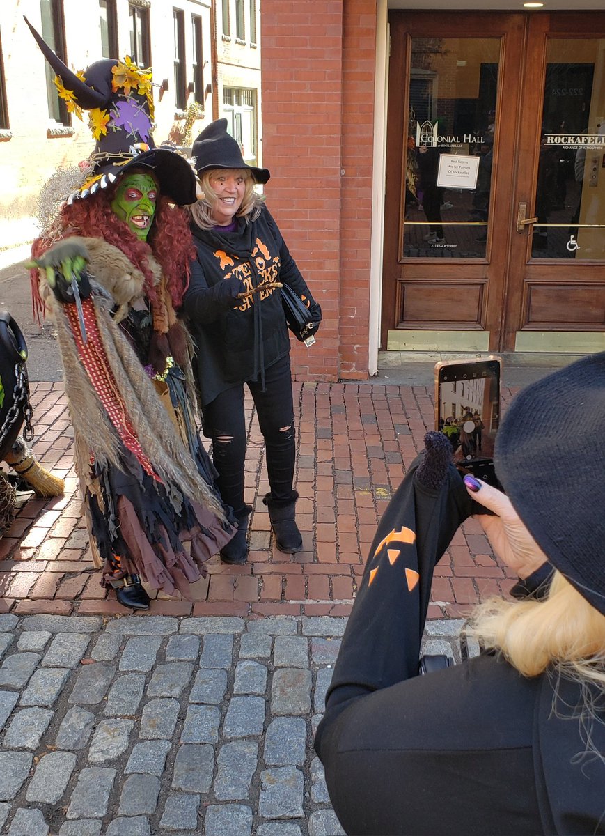 Visiting besties Bonnie Smith (posing) and Cheryl La Due (holding the phone) pose for a photo with Borah of Salem's Black Hat Society early into the festivities Tuesday.
