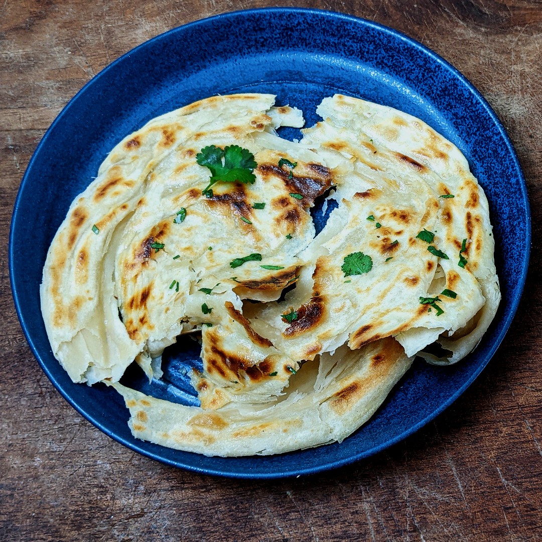 I had some unleavened dough leftover from recipe testing this morning, so rolled it out thin, brushed all over with veg oil, rolled it up and coiled it tightly, then rolled it out again, as you would for a scallion pancake. Pan-fried, garlic butter, coriander, flaky salt, YUM.