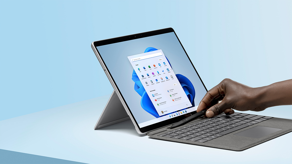 A hand reaches for a digital pen on a Microsoft Surface tablet computer running Windows 11.