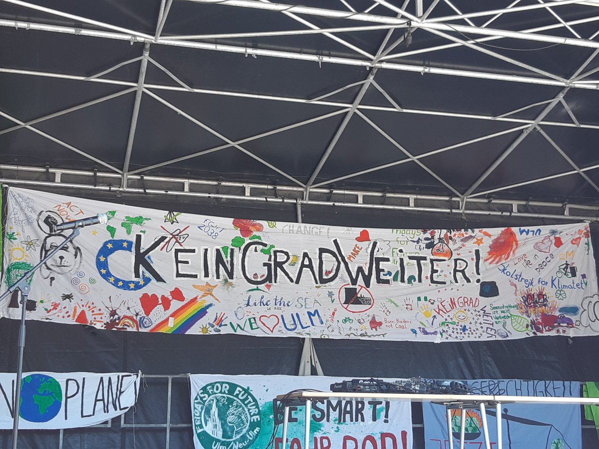 Eine Bühne, daran hängt ein Transparent mit unter anderem der Aufschrift, kein Grad weiter