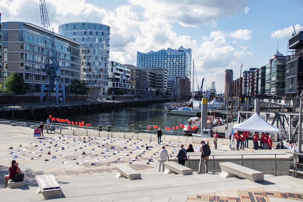 Blick aus der Ferne auf alle aufgereihten Schuhe auf den Magellan-Terrassen bei Sonnenschein.