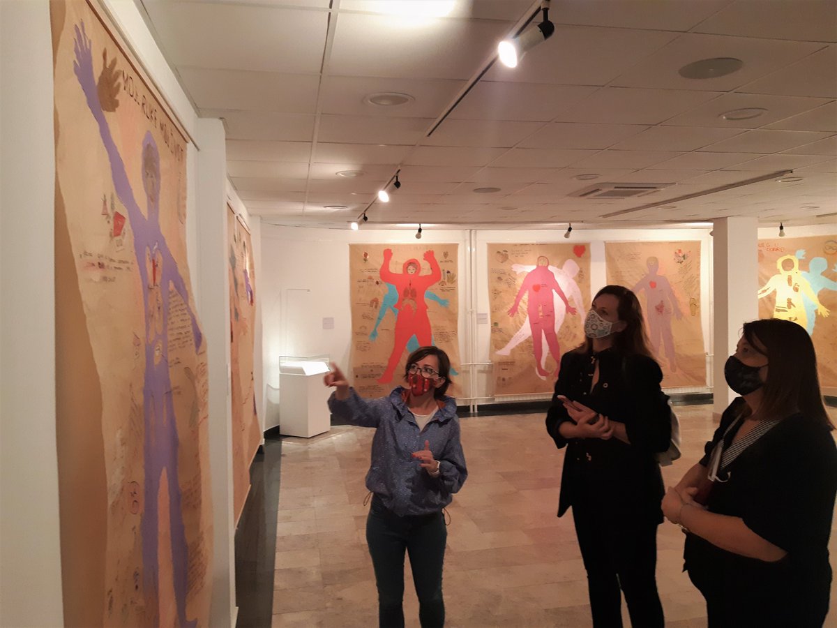 WCM's Project Coordinator is highlighting one of the exhibited body maps of survivors of conflict-related sexual violence to the visiting delegation. Part of the exhibition space (and 5 more maps) are visible in the background.