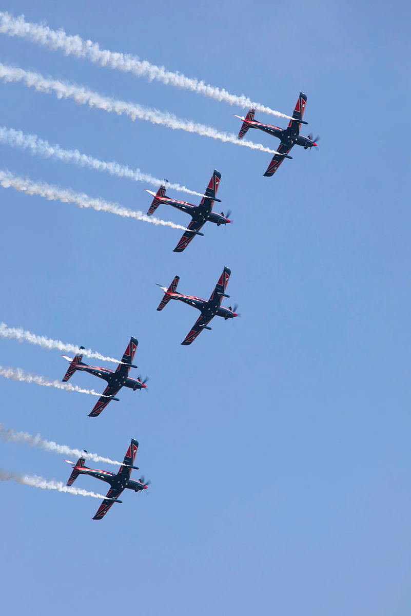 Five aircraft in flight with smoke trails.