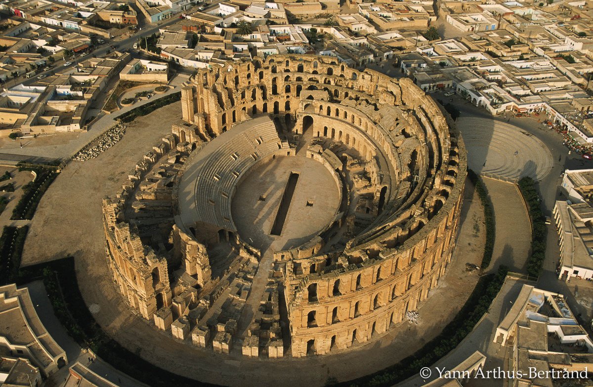 AfrikyaTN's tweet photo. up in the air to unveil the oval #amphitheater in all its majesty, second of its kind in the #Roman empire, standing intact as millennia roll on, here in #Africa's Thysdrus, today's El Jem, eastern #Tunisia, explored and shot by @Yann_A_B https://t.co/v75DHeHQmJ