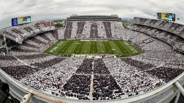 Image of a large football stadium where each section is wearing a different color alternating between blue and white