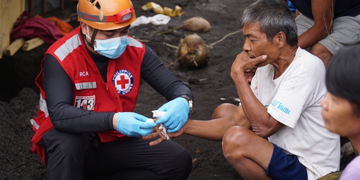 Philippine Red Cross worker administers first aid to a man impacted by an emergency. 