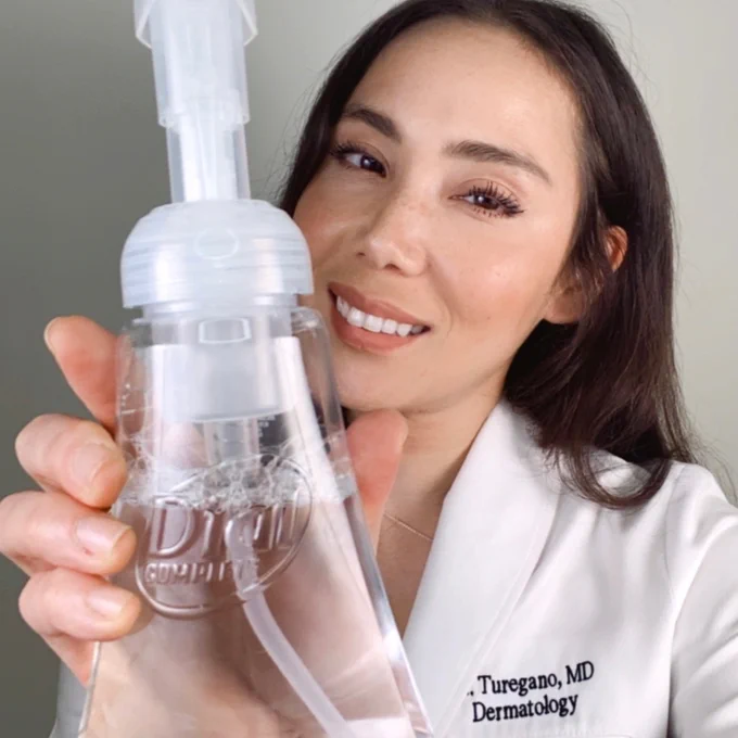 Dr. Mamina holds up Dial Clean + Gentle Foaming Hand Wash and smiles