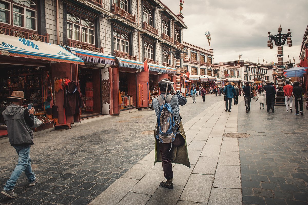 Photograph of people walking through a busy Tibetan street.