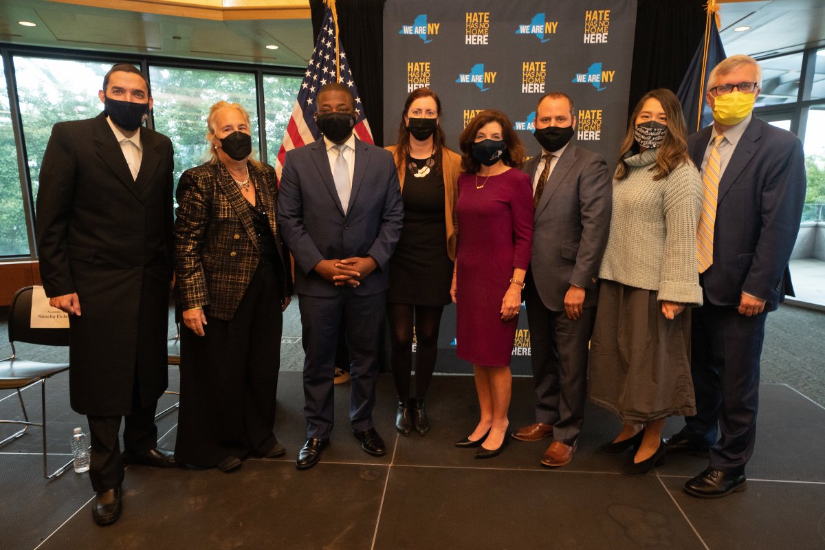 Governor Hochul stands in line with seven other individuals indoors at the Museum of Jewish Heritage