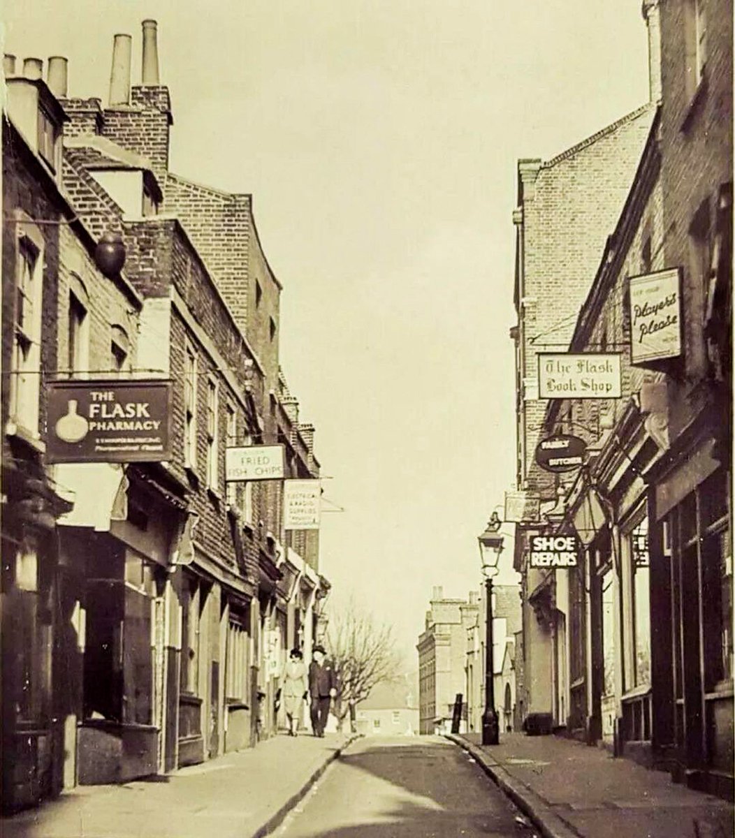 HeathgateUK's tweet photo. Flask Walk, c.1950. #FlaskWalk was still a through route from #HampsteadHighStreet, as there is still a roadway, albeit a very narrow one!

Fascinating to look at the shops back then, a pharmacy, fish &amp; chip shop, shoe repair shop, a butchers &amp; cookware shop.

#historichampstead https://t.co/0j3xyZF2MI