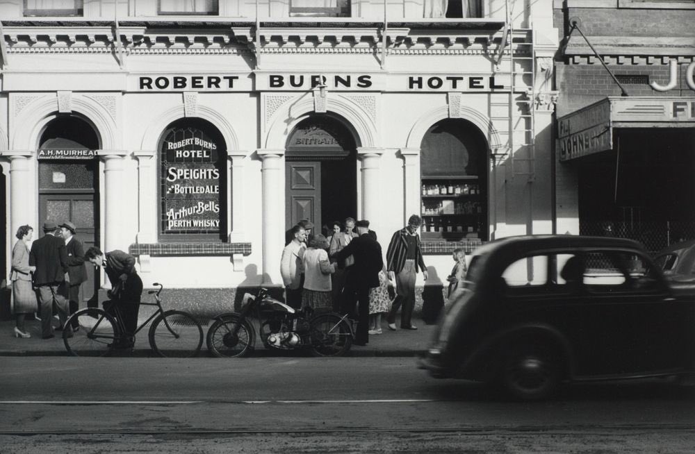 StephenClarkeNZ's tweet photo. On this day in 1967 a legacy of the First World War—six o’clock closing at hotels—finally came to an end. In this wonderful Gary Blackman photo of the Robert Burns Hotel, George Street, Dunedin in November 1952, women and a girl wait outside for the men. (O.030385 Te Papa) #OTD https://t.co/eUByRlpCMS
