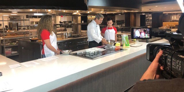 Three people cook while a camera records them.