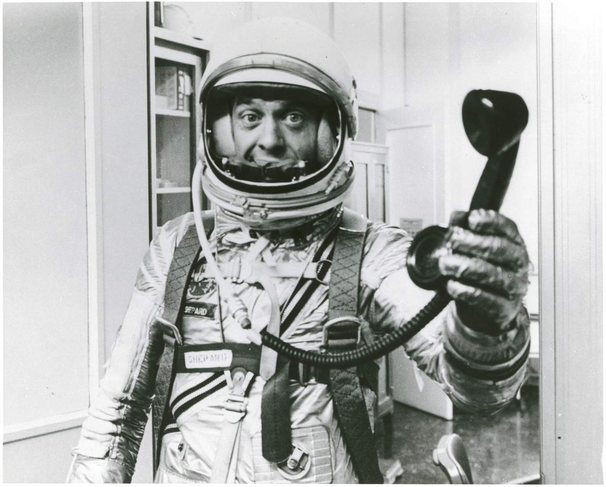 Man in spacesuit holding a corded phone receiver.