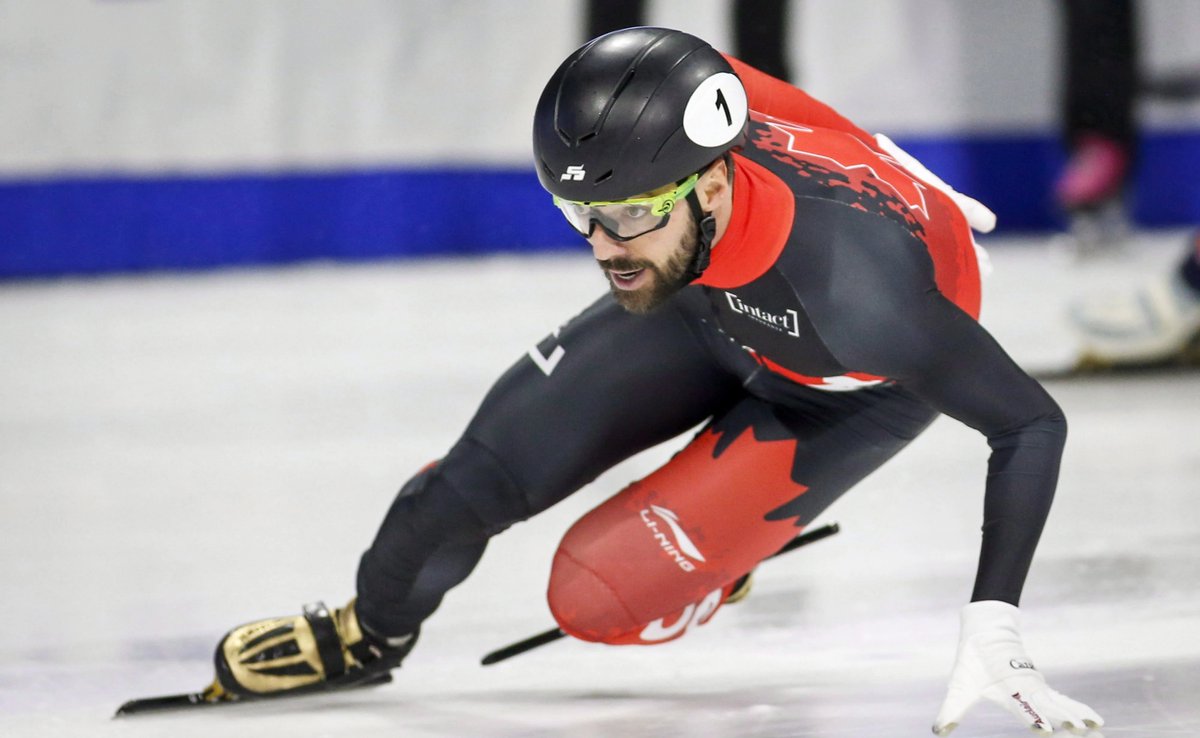 Short track speed skater Charles Hamelin touches the ice with his left hand while skating.