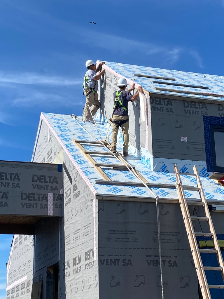 NPTRE's tweet photo. Blue skies as our crew installs the Delta multiband tape used as a transition between the Delta Vent Sa WRB and the Carlisle WIP 300. All of these products help to air seal at our #seapowetbuild
#constructioncrew #NPTREdesignbuild #zeroenergyhome #customhome https://t.co/0rus6msG1t