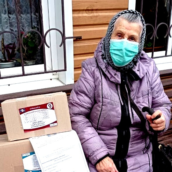 Eine ältere Frau sitzt neben Hilfspaketen