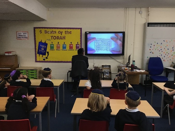 Year 2 watching as Rabbi Katz affixed a Mezuzah on the new KS1 JS classroom. They were fascinated to see a real Mezuzah scroll.