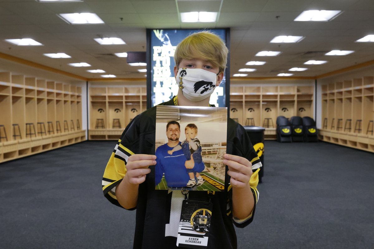 Ayden Gendreau holds a picture of him and his late father as he stands inside the Iowa Hawkeye football locker room.