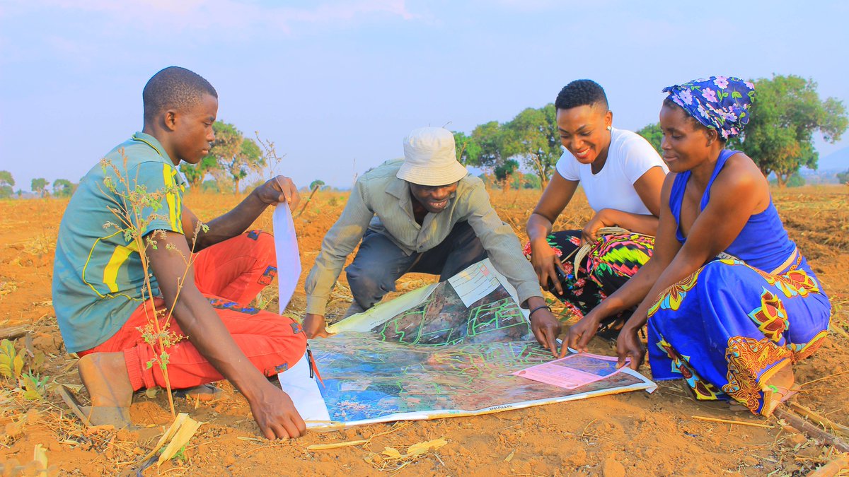 The gender and social inclusion officer of Chipata District Land Alliance goes over a boundary map with a family in Chipata, Zambia.