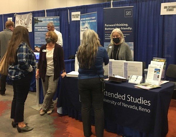 UNRGaming's tweet photo. Extended Studies staff members JoAnne Gipson (facing, left) and Sandy Best (facing, right) talk to prospective students today at the NCET Small Business Expo, which continues until 4 p.m. at the Reno-Sparks Convention Center. #UNR #ProfessionalDevelopment #NCET #ExtendedStudies https://t.co/bnwbnfkazX