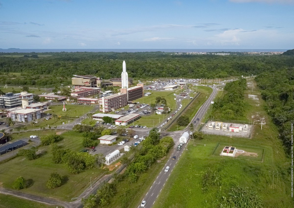 An aerial shot of the Guiana Space Center, with several buildings and a large rocket visible.