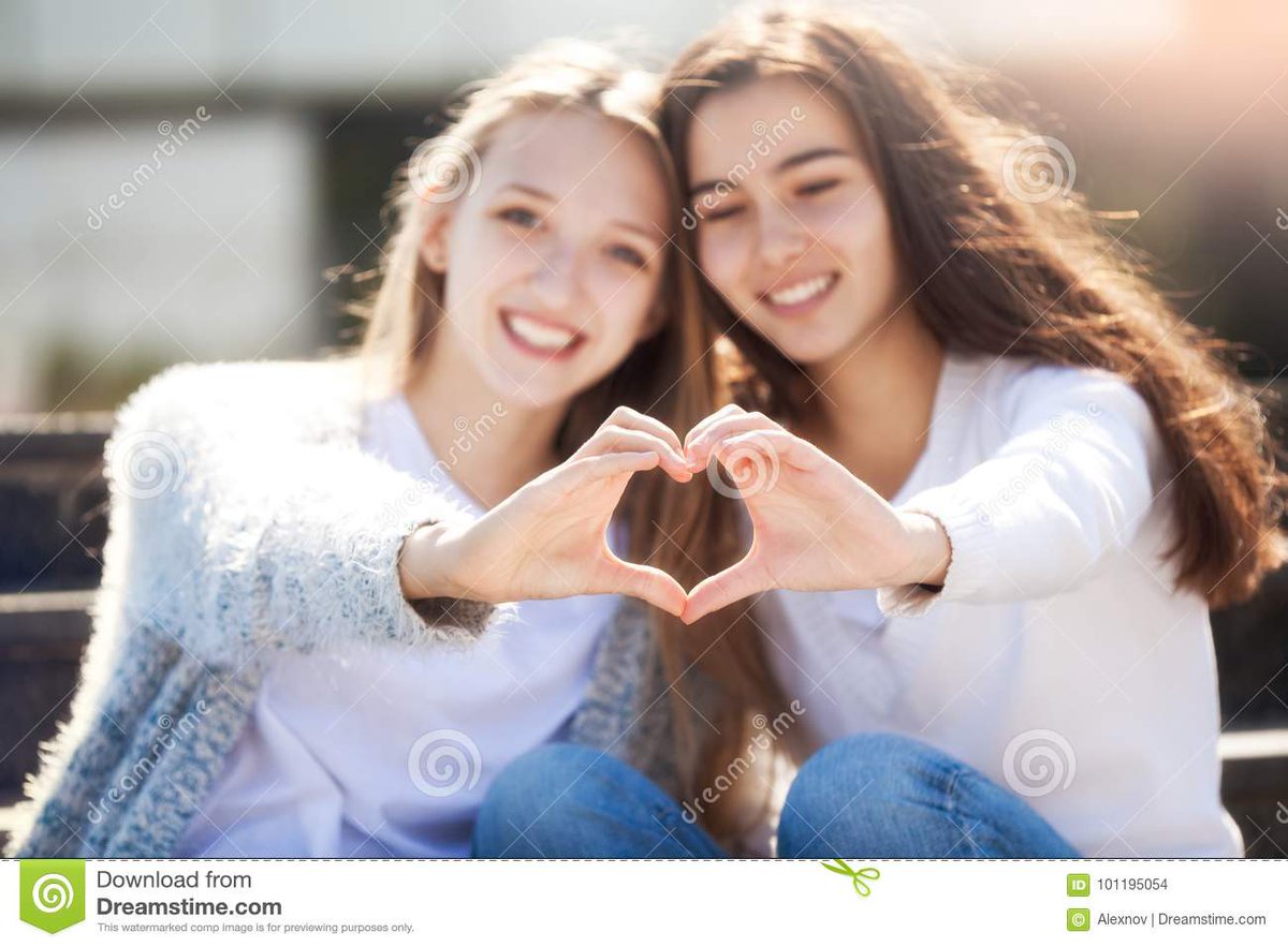 Две женщины обнимаются стоя. Две юные подруги. Две девушки держатся за урки. Любовный треугольник. Девушки держатся за руки.