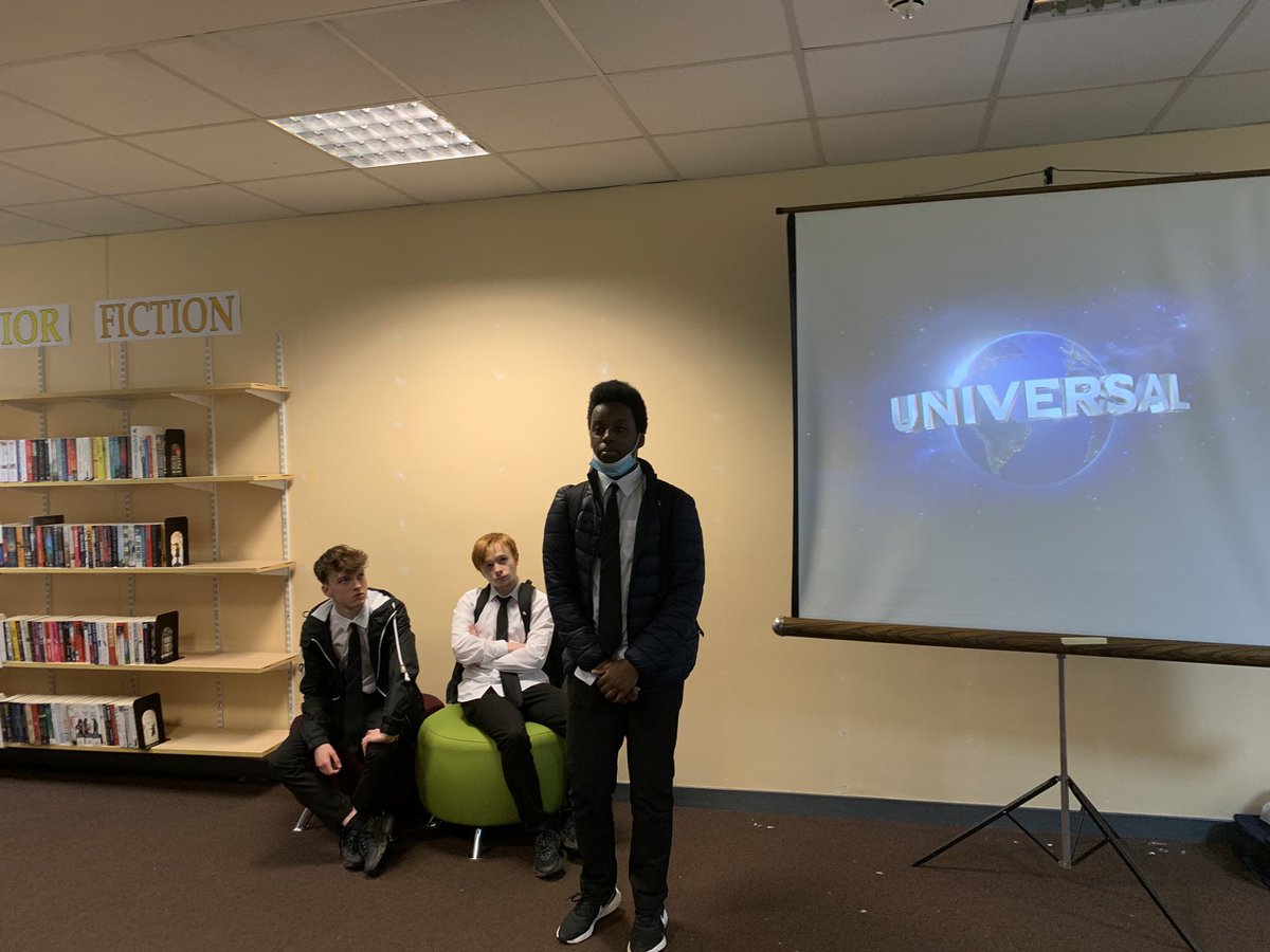 Pupil standing next to screen, introducing film to group.