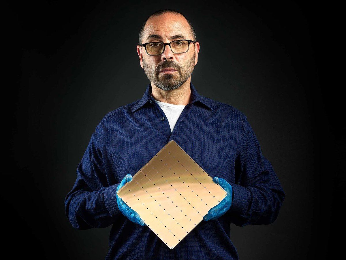 A man holding a very large square silicon chip that is larger than his head.