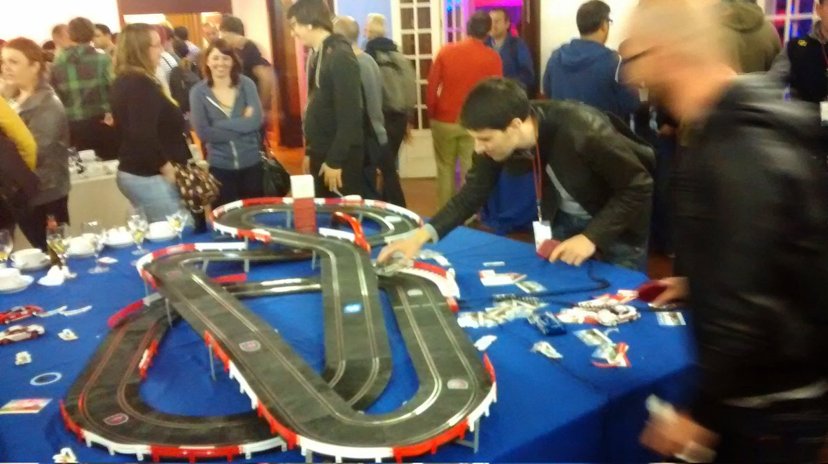 People around a table playing with a remote control slot car track