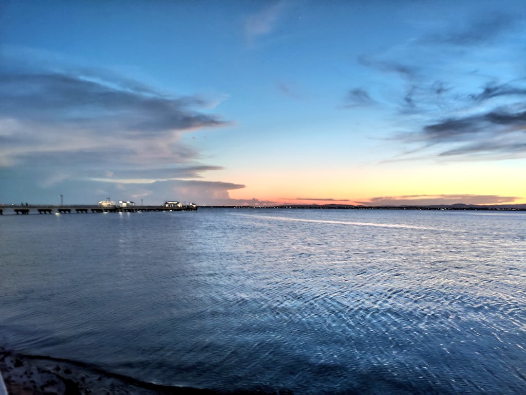 An ocean scene with a pier at dusk