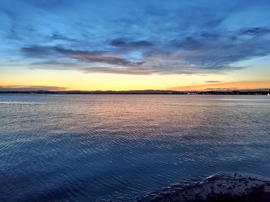 The ocean at dusk with the lights of Brisbane in the distance