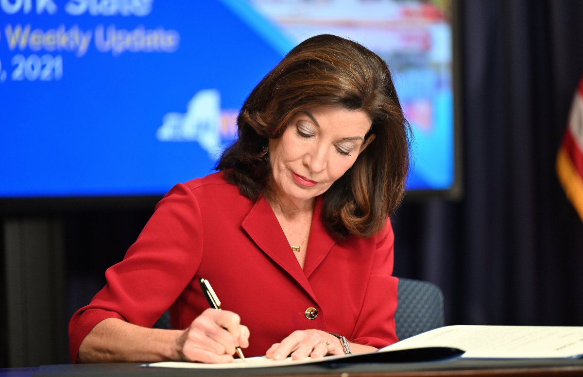 Governor Hochul sits at table signing new piece of legislation