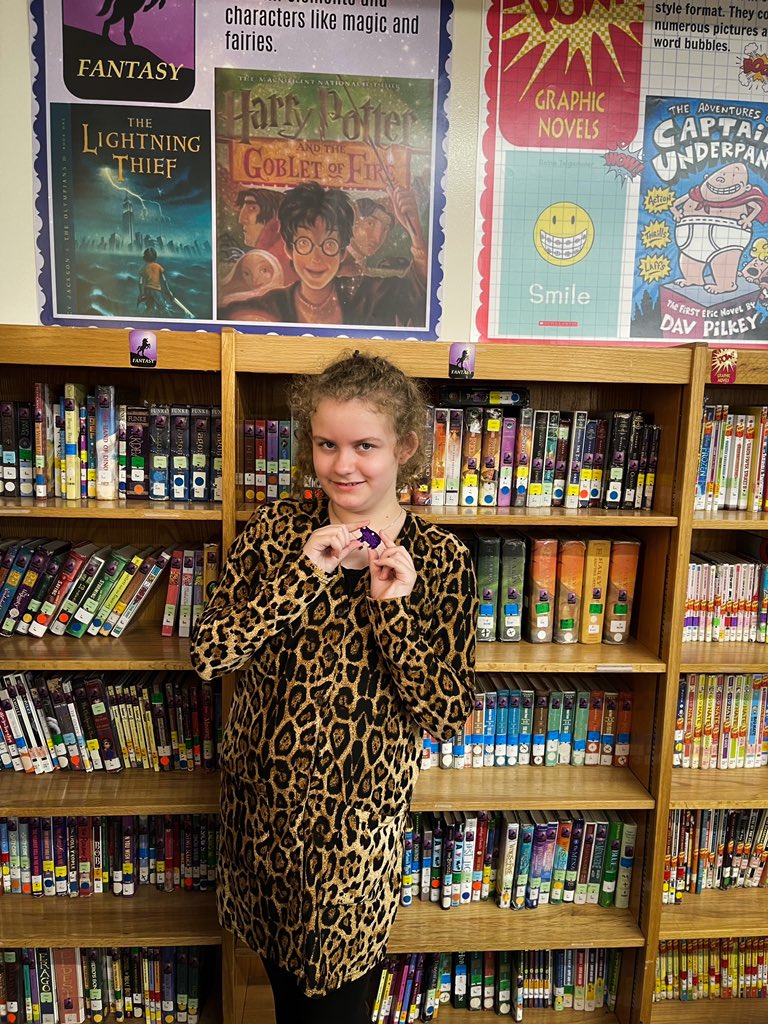 rhogrubb's tweet photo. Ophelia just earned a purple pig!! Sheβs the 1st student this year to get her 100 pt reading tag. Way to go, Ophelia! Keep reading! Fantasy is her favorite genre so she asked to be photographed in front of this section. πππ @CrescentElement #GSCS100N1 #CrescentReads #gscsela https://t.co/cSblatefQn