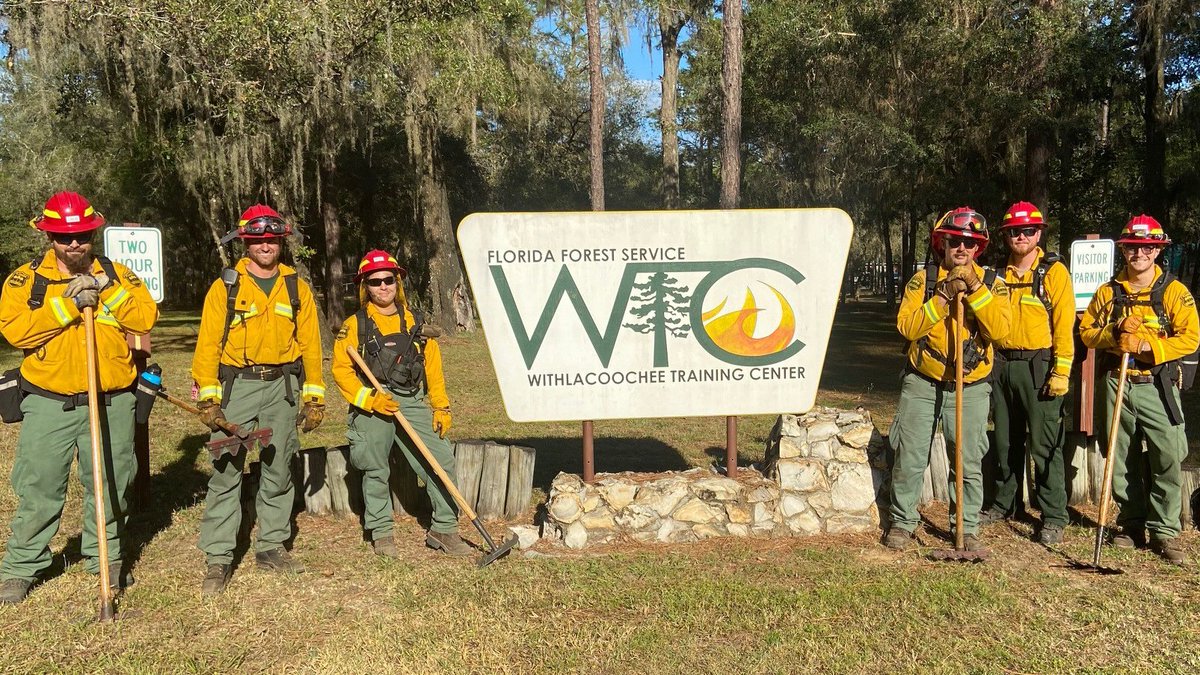 Firefighters pose next to a sign. 