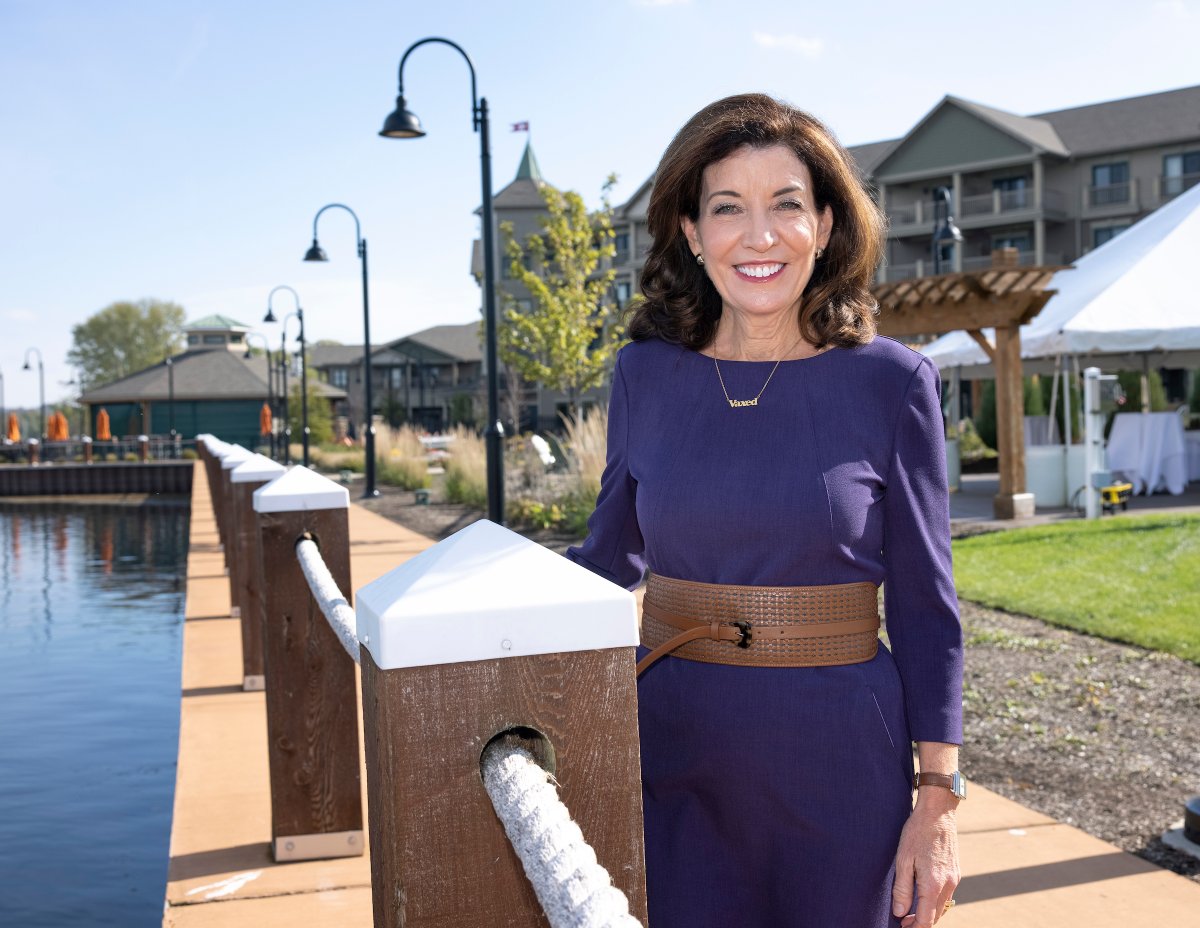 Governor Hochul stands outdoors wearing a purple dress
