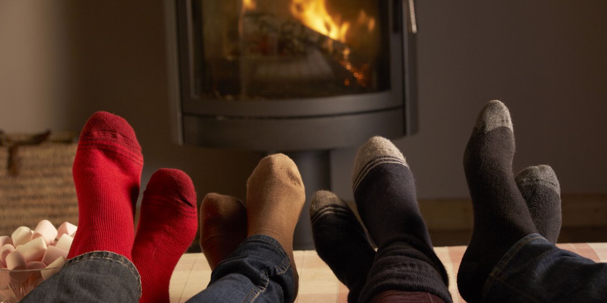 Four pairs of feet resting on sofa  in front of a warm gas fire