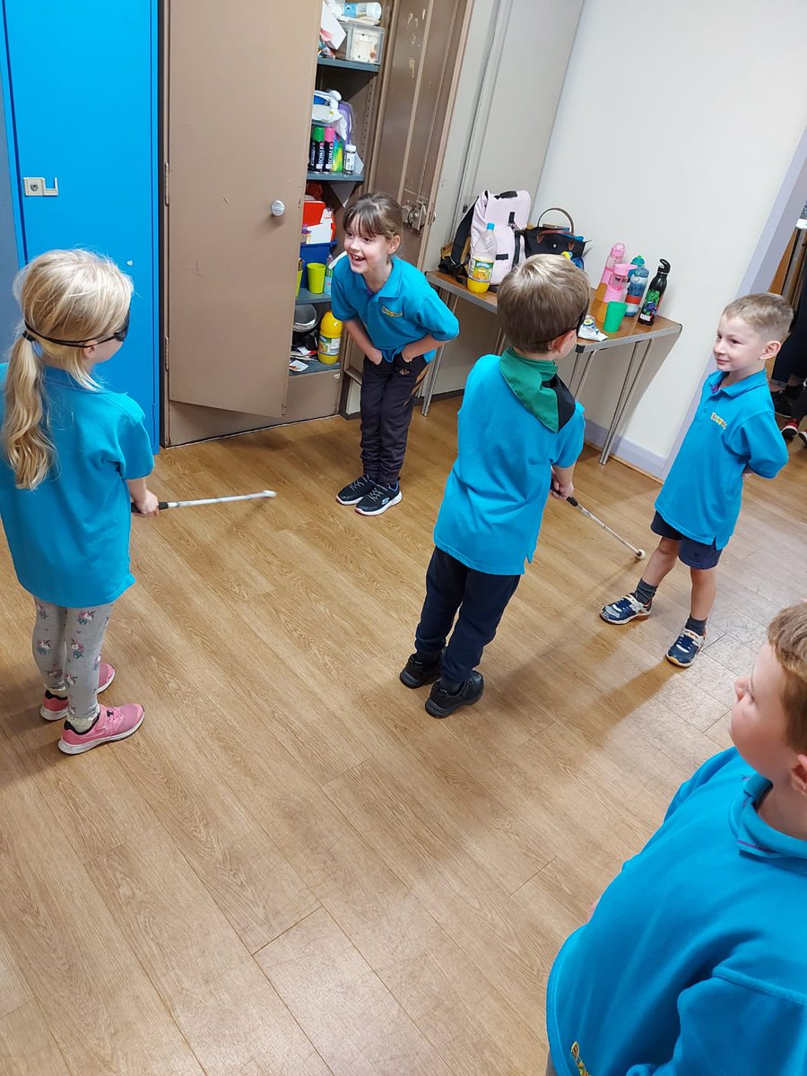 a young girl wearing a blindfold and using a long white cane.