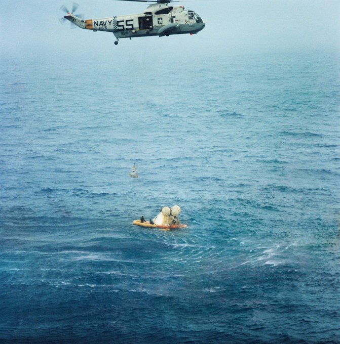 Helicopter hovering over a command module in the water