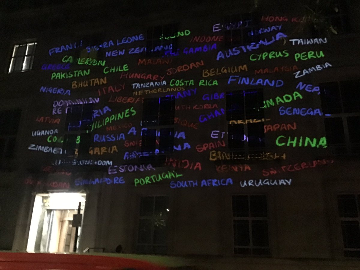 The names of around 100 different counties projected in neon on the front of the LSHTM building.