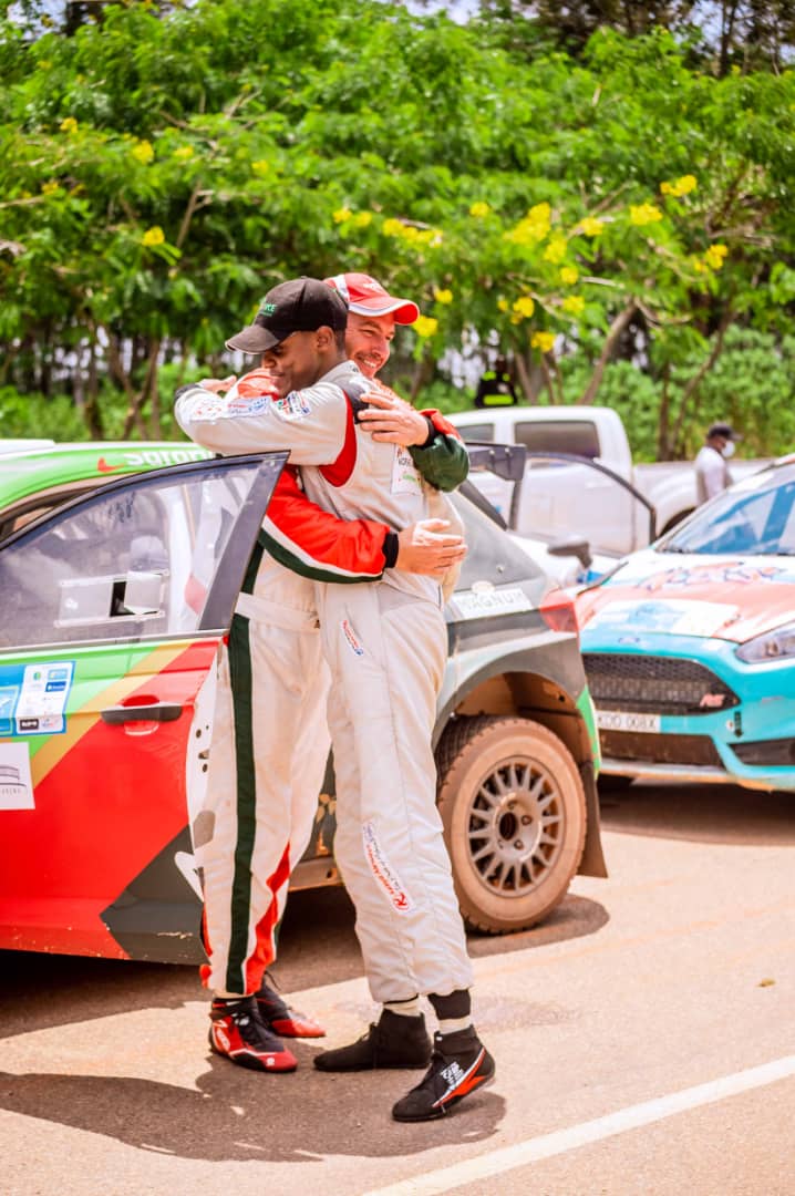 MotorsportRw's tweet photo. No Love Lost: Kenya's McRae Kimathi (in black cape) and Carl Tundo hug each other after the #RMGR. Tundo came out as number 1, and McRae was number 3. #AfricaRallyChampionship https://t.co/2bf77Lhzxm
