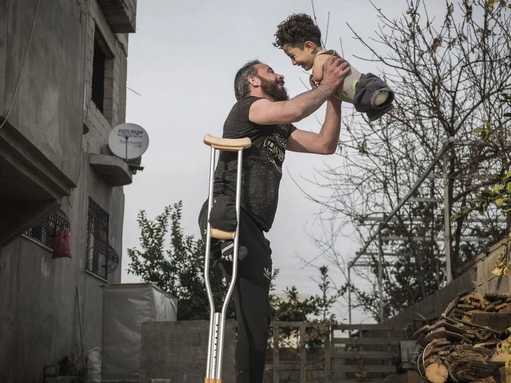 elinlestrange's tweet photo. Mehmet Aslan har vunnet årets bilde i Siena International Photo Awards, med dette bildet av en far og en sønn i Syria. Mustafa er fem år gammel. Han ble født uten armer og bein fordi moren ble utsatt for nervegass under krigen i Syria. https://t.co/NsKaG8XQ3U
