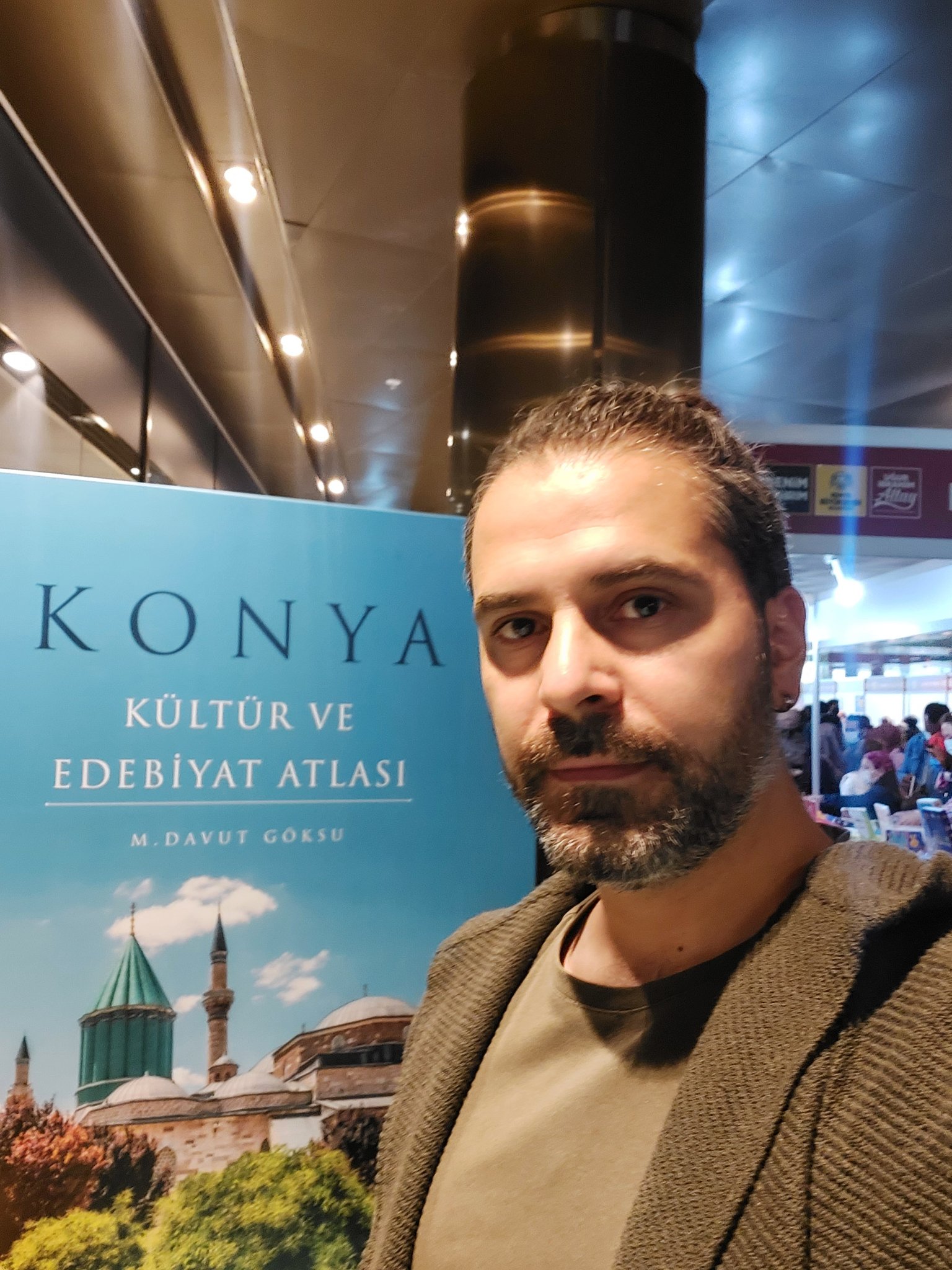 Mustafa Göksu, Konya Kültür ve Edebiyat Atlası broşürünün önünde poz veriyor