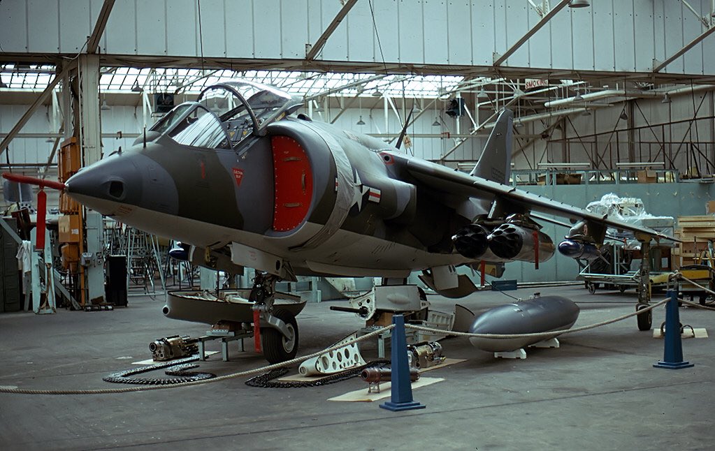 HarrierPres's tweet photo. Circa 1975, some shots of AV-8A production, looking at the hangar, I’d say this is Dunsfold, note the twin MATRA rocket pods, on the inner pylon, and the tall tail of a TAV-8A on the second image. #AV8A #HarrierGR1 #HawkerSiddeley https://t.co/SAAI2lJMgp