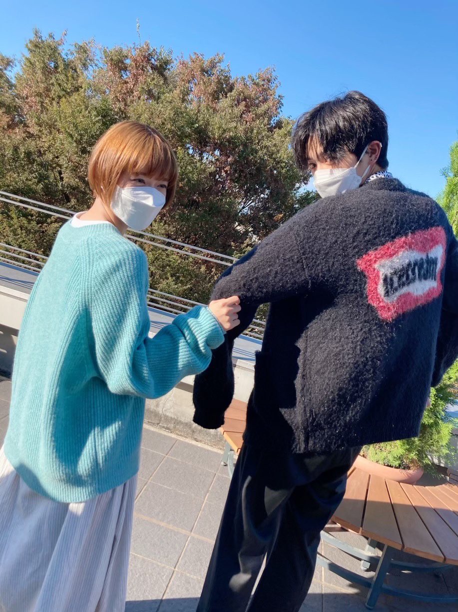 ユキコとモリオの振り向きオフショット写真。左側にユキコ、右側にモリオがいる。２人とも白いマスクをしている。ユキコは右手で、モリオの左手のひじのあたりに手を添えている。２人ともカメラの方に背中をむけて、顔だけ振り向いている。ユキコはミントブルーのニットに白のロングスカートをきている。モリオは黒のカーディガン、黒の長ズボンを履いている。