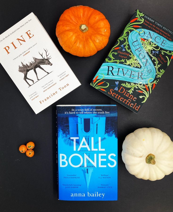 Image: https://pbs.twimg.com/media/FCuKkSSWYAoTUdn?format=jpg&name=900x900 Three books lie in a triangle shape on a black background Pine by Francine Toon Tall Bones by Anna Bailey and Once Upon a River by Diane Setterfield An orange pumpkin a white pumpkin and three small pumpkin shaped wrapped chocolates sit in between the books